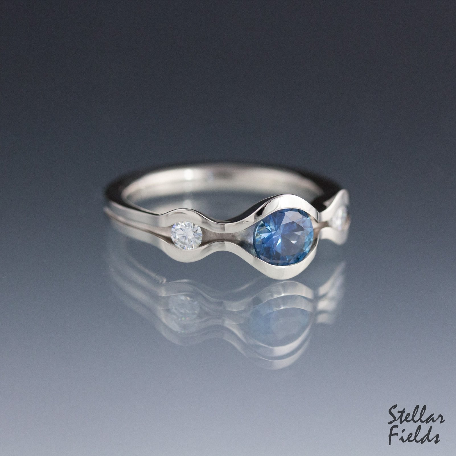 blue montana sapphire three stone engagement ring with diamond accents modern wave design stellar fields jewelry